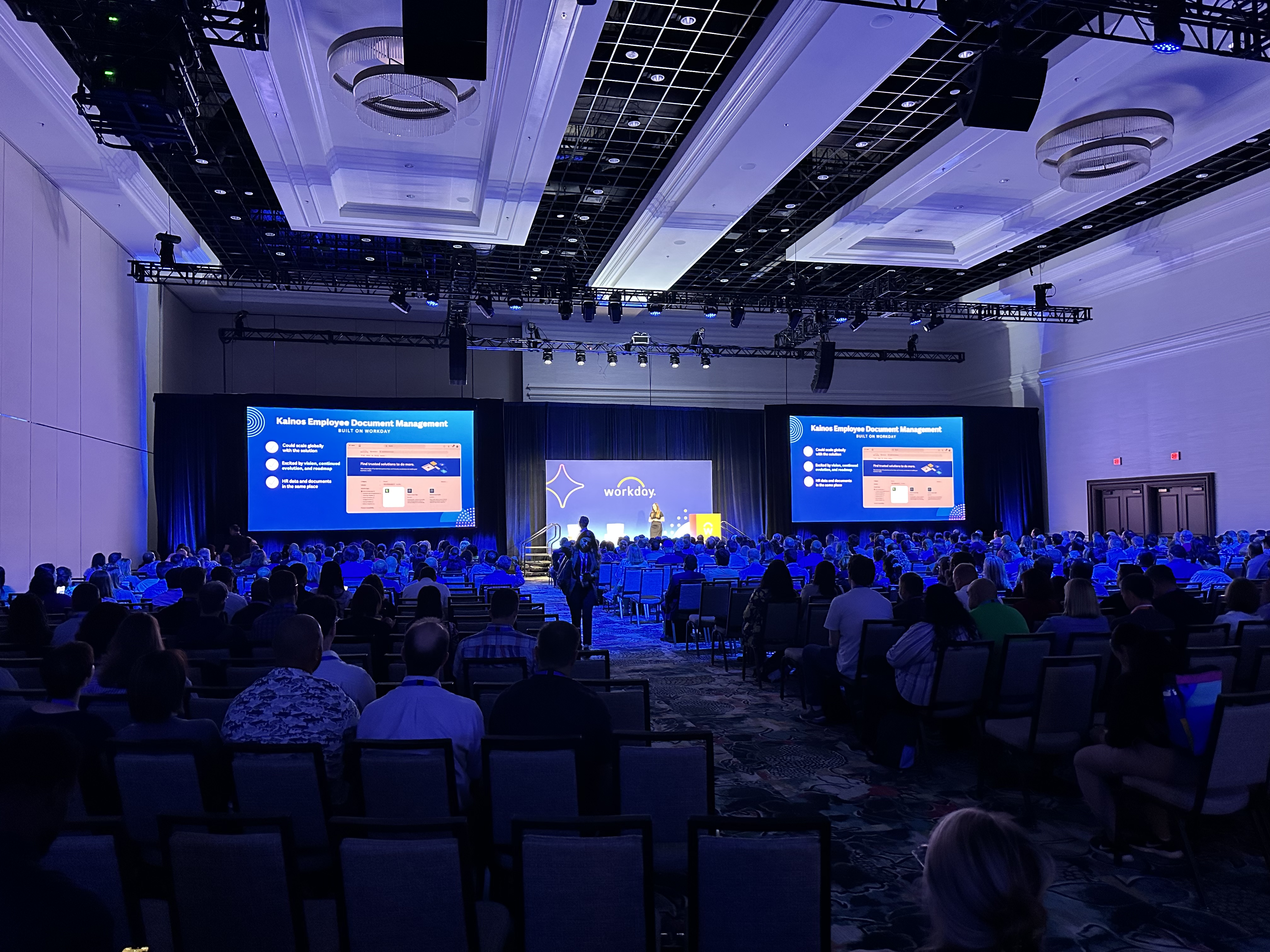 A small general session with two screens and a stage for presenters.